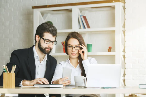 Hombre de negocios y mujer enfocados usando teléfono inteligente — Foto de Stock