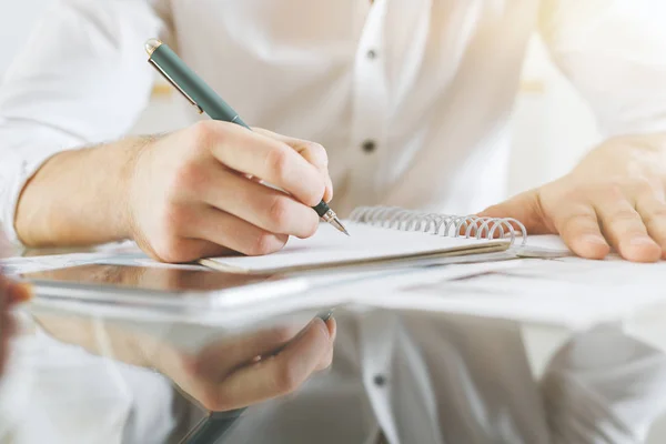 Primer plano de manos masculinas haciendo papeleo en el escritorio de la oficina de vidrio con teléfono inteligente. Concepto de trabajo —  Fotos de Stock