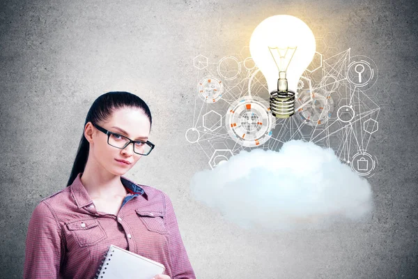 Attraente donna d'affari con lampada luminosa astratta, ologramma aziendale e nube su sfondo concreto. Concetto di innovazione — Foto Stock