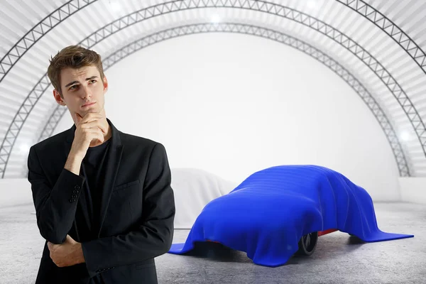 Thoughtful businessman in warehouse interior with car under cloths. Designer concept. 3D Rendering — Stock Photo, Image