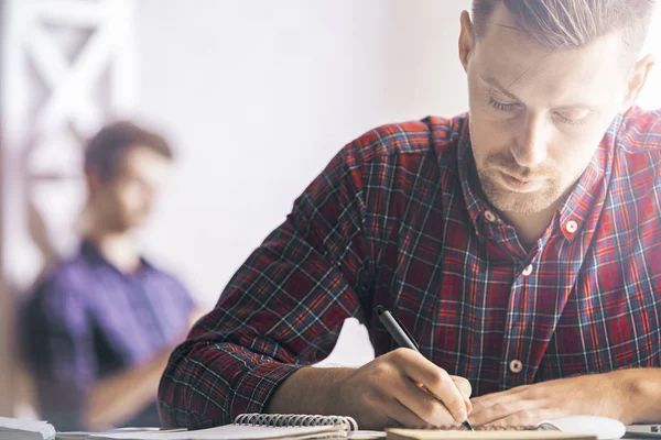 İşyerinde sarmal Defteri'nde yazma yakışıklı beyaz adam portresi. Evrak kavramı. İçinde belgili tanımlık geçmiş bulanık meslektaşım