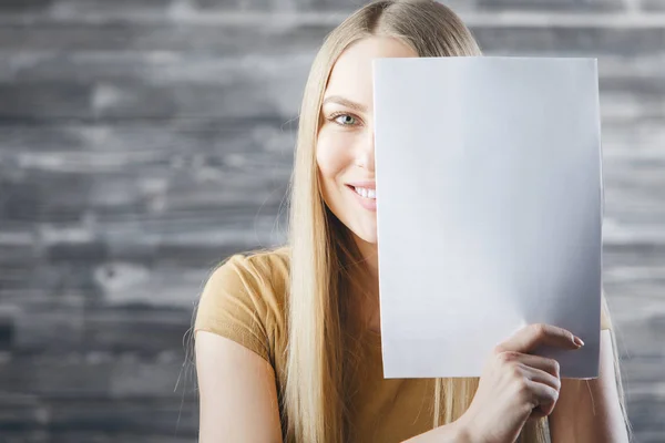 Mujer cubriendo la cara con papel vacío — Foto de Stock