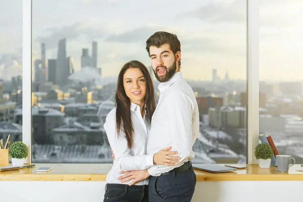 ぼやけてシティー ビューのモダンなオフィスのインテリアにカップルを抱き締めることの側面図です。ロマンスのコンセプト — ストック写真