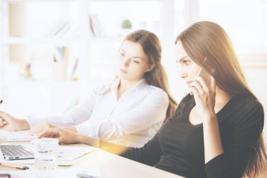 İş kadınları dizüstü kullanarak telefon