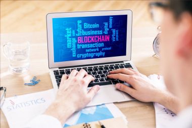Blockchain Web sayfası, rapor, su cam ve diğer öğeleri ile ahşap ofis masaüstünde yer ile dizüstü bilgisayar kullanarak bir iş adamı. Gelecekteki kavramı 