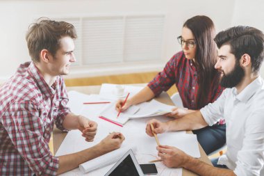 Evrak işlerini yapıyor ve aygıtlarını kullanarak gülümseyen insanlar 