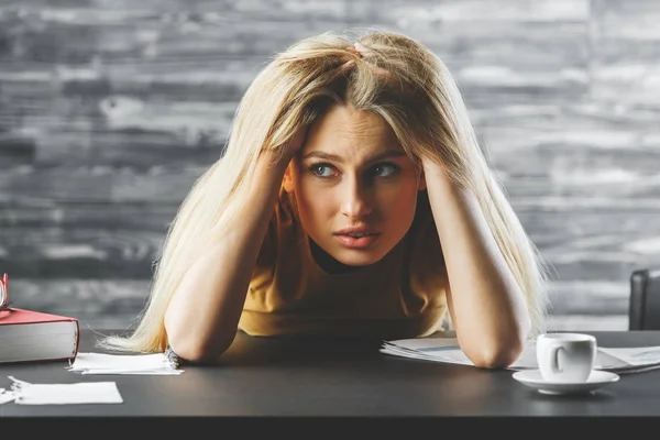 Retrato de una joven preocupada en el escritorio de la oficina con taza de café y otros artículos. Concepto de estrés — Foto de Stock