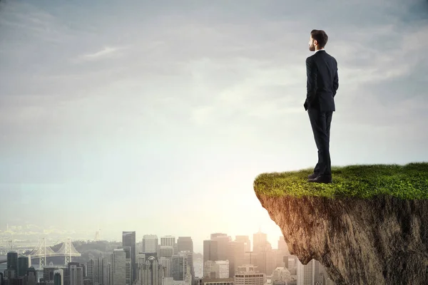 Young businessman standing on cliff — Stock Photo, Image