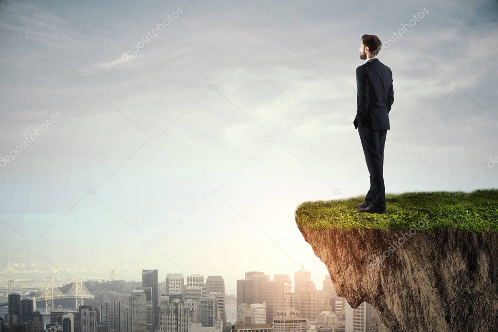 young businessman standing on cliff 