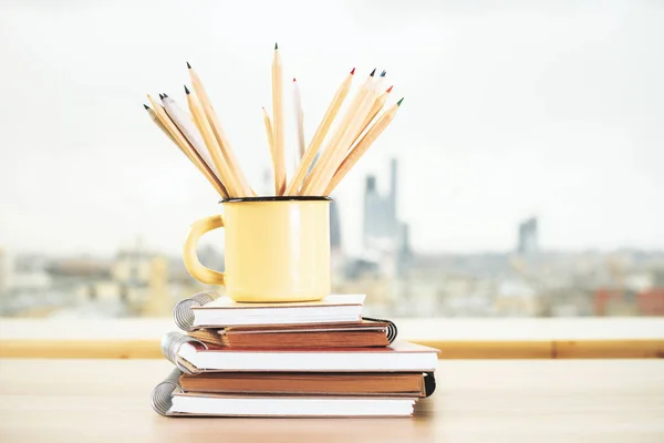 Iron mug with pencils and copybook — Stock Photo, Image