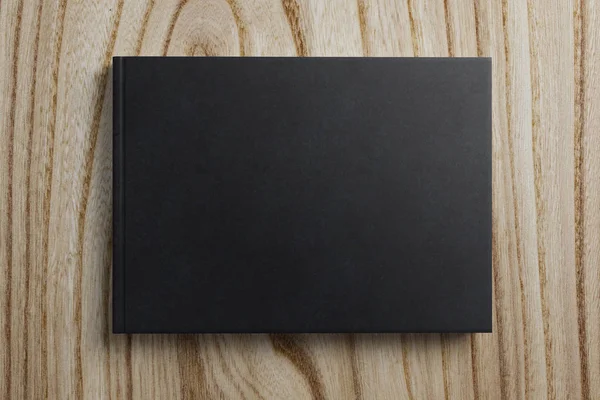 Άδειο μαύρο βιβλίο σε φόντο ξύλινη — Φωτογραφία Αρχείου