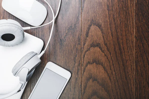 Headphones and device on wooden desk — Stock Photo, Image