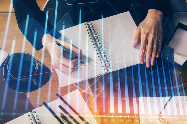 Forex graph on hand taking notes background. Concept of research. Multi exposure