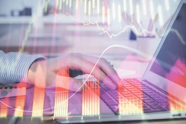 外国為替グラフの背景を持つ株式市場のラップトップでメモを書く男の手の二重露出。トップビュー。研究と取引の概念. — ストック写真