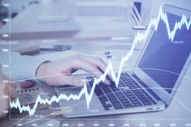 Arka planda dizüstü bilgisayar üzerinde çalışan adam ile borsa grafiği çoklu pozlama. Finansal analiz kavramı.