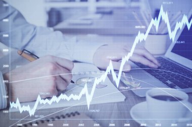 Arka planda dizüstü bilgisayar üzerinde çalışan adam ile borsa grafiği çoklu pozlama. Finansal analiz kavramı.