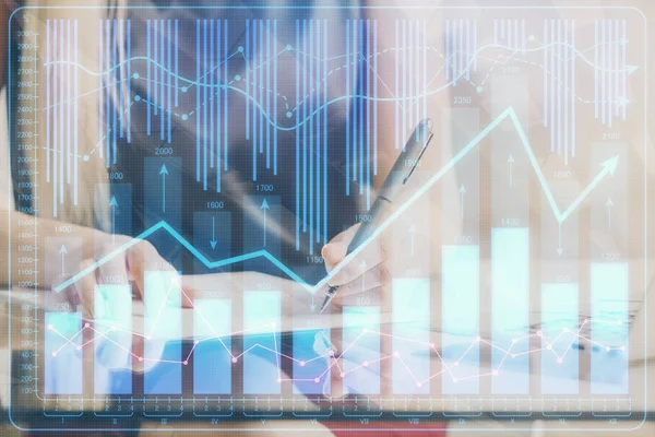 Una mujer escribe información sobre el mercado de valores en bloc de notas. Hologramas gráfico de divisas en frente. Concepto de investigación. Doble exposición —  Fotos de Stock