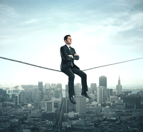 Businessman sitting on rope