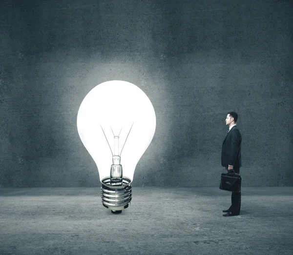 Businessman with case looking on big lightbulb — Stock Photo, Image