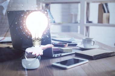 Bilgisayar ofisinde ampul simgesi hologramıyla birlikte. Çoklu maruz kalma. Fikir kavramı.