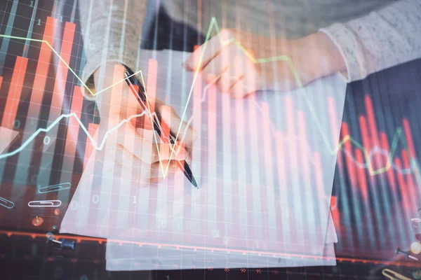 Toma de notas a mano en bloc de notas. Hologramas gráfico de divisas en frente. Concepto de investigación. Exposición múltiple — Foto de Stock