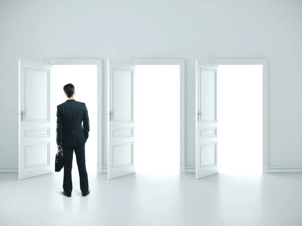 Podnikatel s aktovkou stojící v bílém pokoji — Stock fotografie