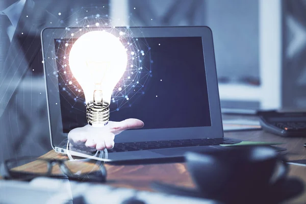 Ordenador en el escritorio en la oficina con el holograma icono de la bombilla. Exposición múltiple. Concepto de idea. — Foto de Stock