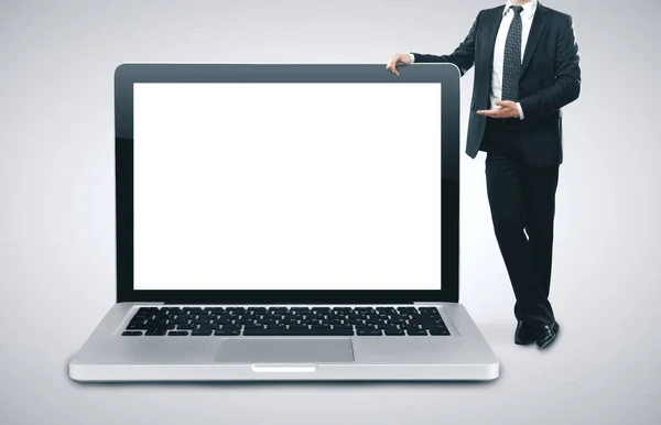 นักธุรกิจยืนกับแล็ปท็อปขนาดใหญ่ . — ภาพถ่ายสต็อก