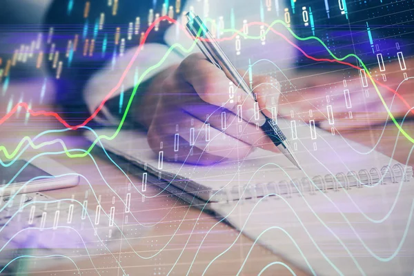 Una mujer escribe información sobre el mercado de valores en bloc de notas. Hologramas gráfico de divisas en frente. Concepto de investigación. Exposición múltiple —  Fotos de Stock