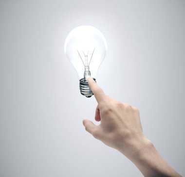 Gri arkaplandaki ampulü elle itme.