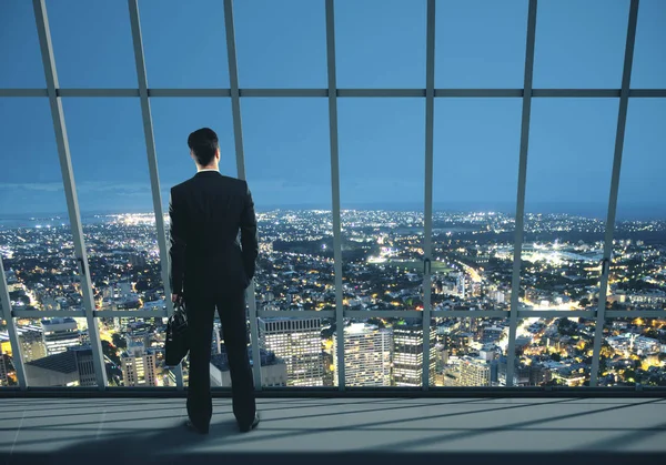 Empresário com caso em pé no escritório noturno — Fotografia de Stock