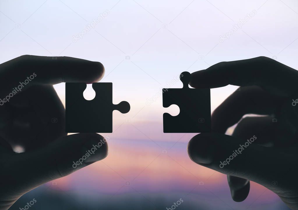 Hands putting puzzle pieces together.