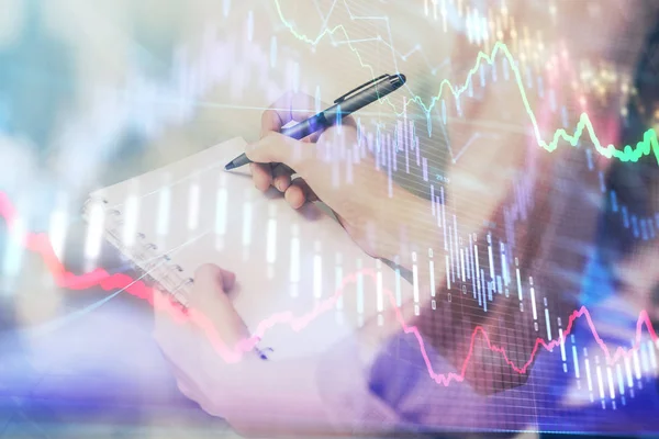 Multi exposure of hands making notes with forex chart huds. Stock market concept.