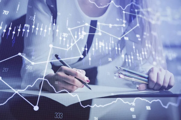 Double exposure of hands making notes with forex chart huds. Stock market concept.