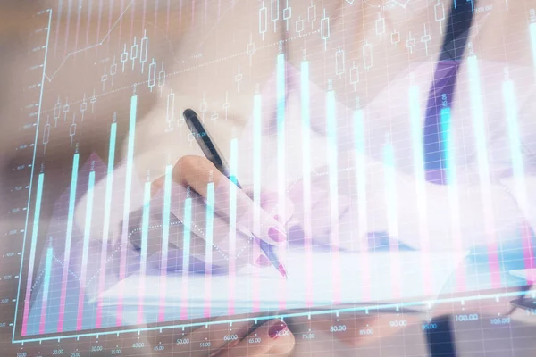 Double exposure of hands making notes with forex chart huds. Stock market concept.