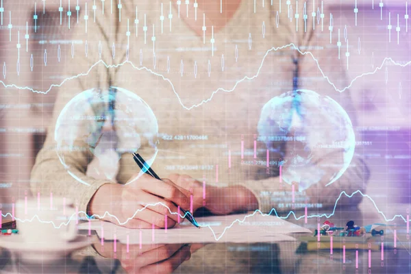 Hand taking notes in notepad. Forex chart holograms in front. Concept of research. Double exposure