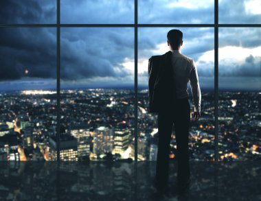 İşadamı gece ofisinde duruyor ve Megapolis manzarasına bakıyor. Meslek ve işçi konsepti.