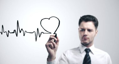 Doktor kalp sembolü çiziyor ve kalp atışlarının grafiğini çıkarıyor. Sağlık ve Tıp Konsepti