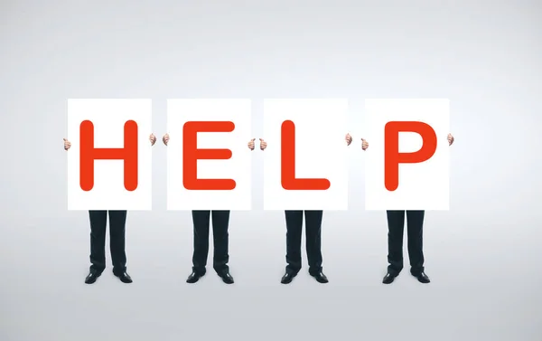 Vier Geschäftsleute Halten Ein Weißes Plakat Mit Rotem Hilfssymbol Der — Stockfoto