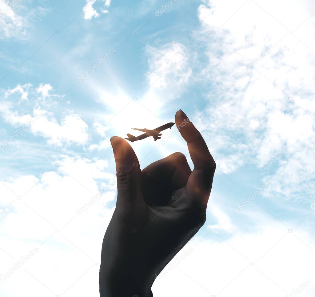 Hand holding airplane on sky background. Transportation and lifestyle concept.