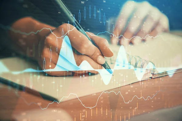 Forex graph on hand taking notes background. Concept of research. Double exposure