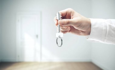 İç mekan arka planında bir iş adamı anahtarı tutuyor. İş ve başarı kavramı.