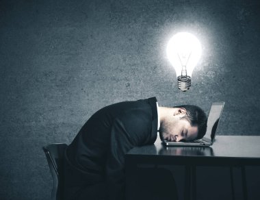 İş adamı kafasında lambayla işyerinde uyuyor. Fikir kavramı