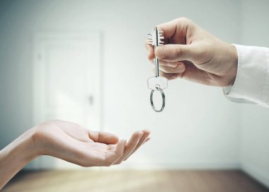 El, evin anahtarını iç mekan arka planına koyuyor. İş ve başarı kavramı.