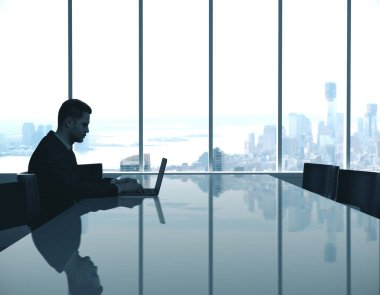 Gece konferansında çalışan genç işadamı şehir manzaralı iç mekan.