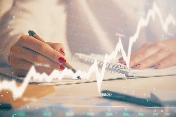 外国為替グラフホログラムでノートを作る女性の手の二重露出。コンセプト株式市場分析. — ストック写真