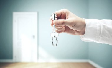 İç mekan arka planında bir iş adamı anahtarı tutuyor. İş ve başarı kavramı.