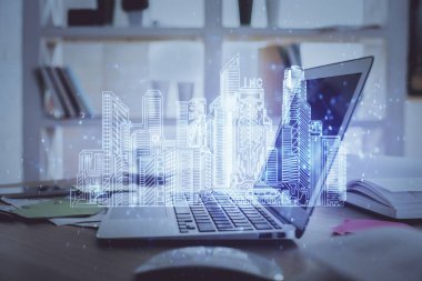 Ofisteki masaüstü bilgisayar geçmişi ve büyük kasaba binaları hologram çizimi. Çifte maruziyet. Akıllı şehir konsepti.