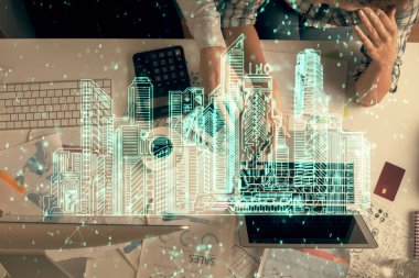 Kadın ve erkeğin birlikte çalıştığı ve binaların hologram çizimlerinin çifte pozlanması. Bilgisayar arkaplanı. Üst Manzara. Akıllı şehir konsepti.