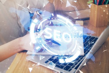 Kadın elinin SEO simgesiyle notlar alırken çoklu pozlanması. Arama motoru optimizasyonu kavramı